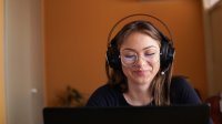 Woman works at her laptop wearing headphones