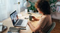 Woman participating in a group video chat while drinking coffee