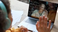 Teenager participating in a virtual meeting with her teacher on her laptop