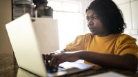 Woman working on her laptop at her kitchen table