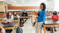 Science teacher instructing her class while all wear masks