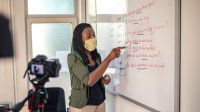 Teacher wearing a mask and leading students in a grammar lesson during hybrid learning