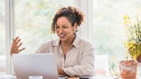 Woman gesturing while working at her laptop at home