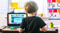 Four-year-old boy working on a virtual learning assignment on his laptop