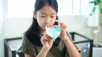 Young girl making a paper airplane at home