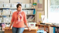 Teacher leaning on her desk and looking out the window