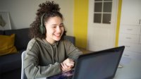 Teenage girl smiling during remote learning class on laptop at home