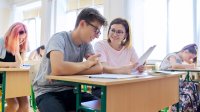 Teacher works with high school student at his desk