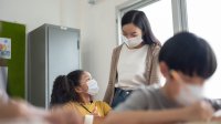 Elementary school teacher speaks with student in classroom