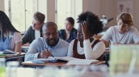 High school teacher helps student at her desk