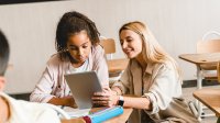 Teacher helps student in middle school classroom