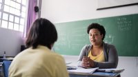 Teacher having a one-on-one conversation with a student at her desk