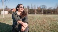 Woman wearing sunglasses sitting in a field enjoying the sunshine