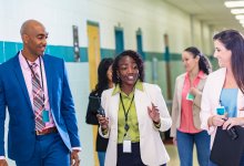 Principal walks and talks with teacher in a school hallway