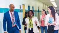 Principal walks and talks with teacher in a school hallway