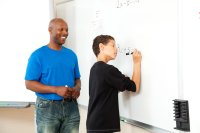 Teacher helping a student with math using white board