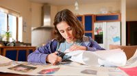 Middle school aged girl working on a school project at home with paper and scissors