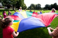 Teacher and students playing with parachute outside