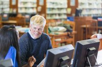 Two teachers talking in a library in front of computer monitors