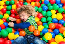 Young child jumps into a colorful plastic ball pit