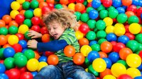Young child jumps into a colorful plastic ball pit