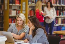 Two teachers working together on a laptop in a school library