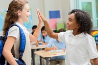 Two elementary students high-fiving in a classroom