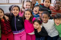 A group of elementary school students laughing together with their arms around each other