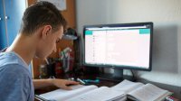 Teenage boy doing homework in front of computer