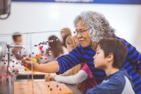 A teacher helping a student with an atom model