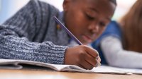 Elementary aged boy at school writing at desk