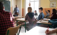 High school students raising their hand in response to a teachers question