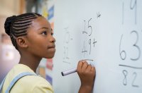 Student working on math problems at a white board