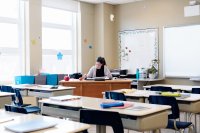 A teacher sitting alone in an empty classroom, grading papers