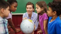 Teacher with elementary students looking at globe