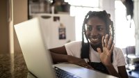 Teenage girl smiling during remote learning class on laptop at home