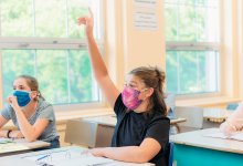 High school girl in classroom holding up hand