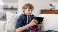 Middle school aged boy reading on tablet at home