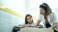 Teacher help student in middle school classroom