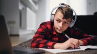 Teen boy laying on floor at home remote learning with laptop