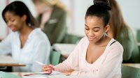 High school student writing in class room. 