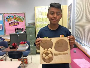 Student poses with his laser engraver creation.