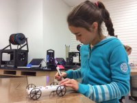 A young girl is sitting in class building a toy car.
