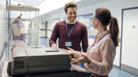 Two adults stand by a copy machine, smiling at each other.