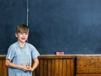 Boy speaking in front of blackboard
