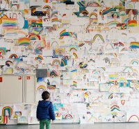 Young child looking at wall covered in rainbow drawings