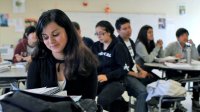 Girl looking at her binder in class with other students