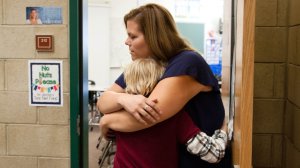 A teacher hugs her student.