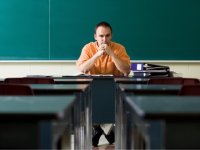 Man sitting at desk in an empty classroom