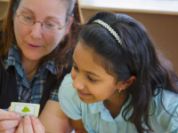 A photo of a female teacher working with an elementary-school girl.